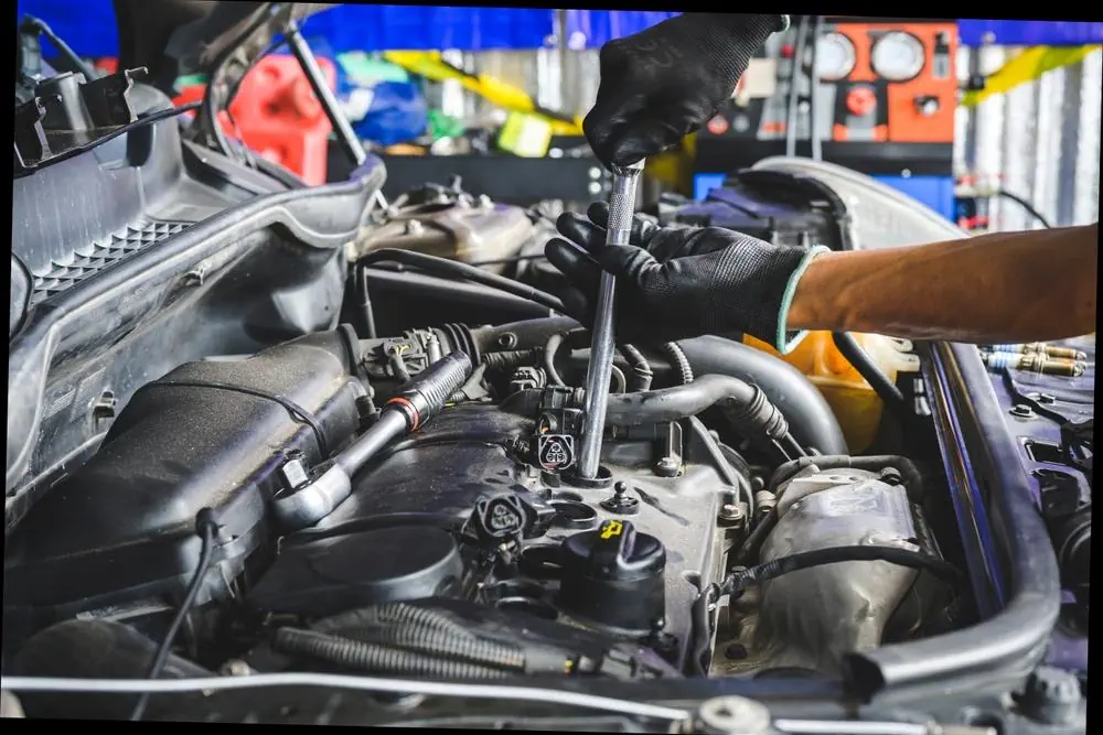 Automechaniker baut neue Zündkerzen in den Motor ein.