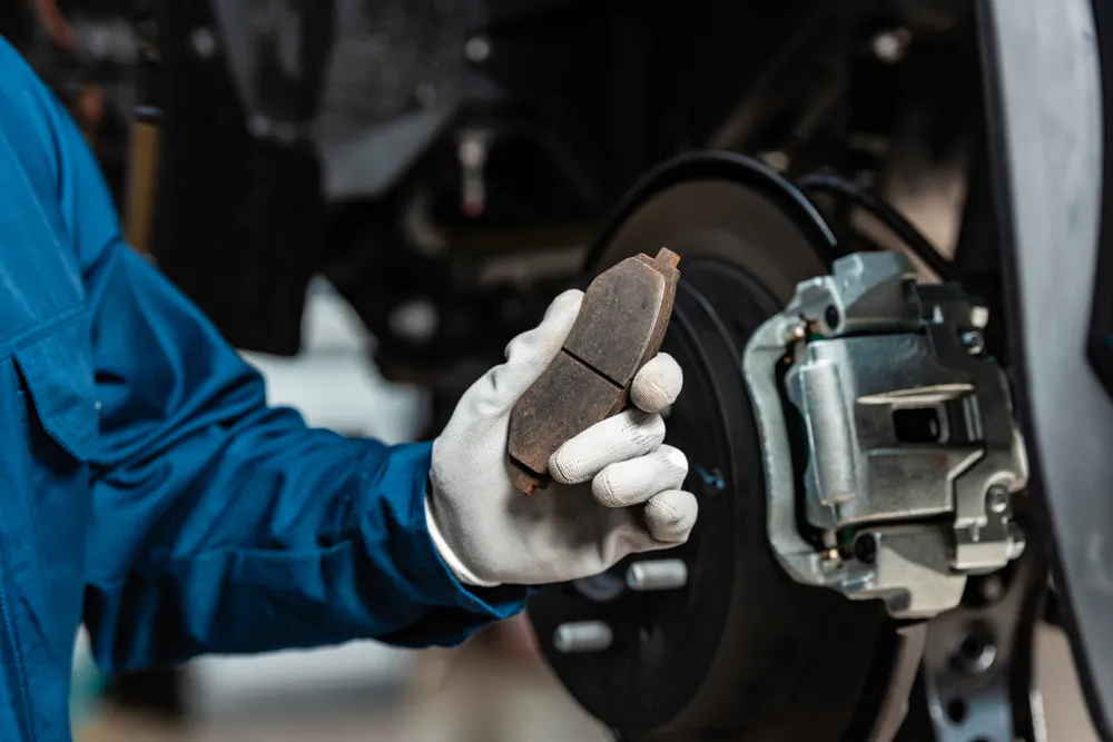 Fahrzeugmechaniker hält Bremsbelag in der Hand Fahrzeugmechaniker hält Bremsbelag in der Hand